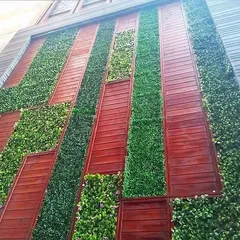 Another example of a mixed-media green wall, combining vertical strips of artificial plants with reddish-brown wood panels for a striking geometric effect.