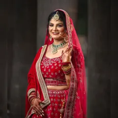 A classic bridal portrait showcasing the elegance of the bride. Her smile and pose radiate happiness and confidence in her beautiful red wedding lehenga.