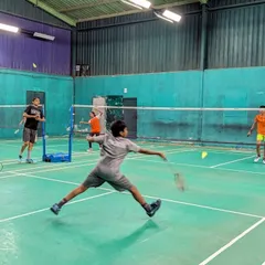 A young player executes a full-stretch lunge to return a shuttle during a training session. We focus on developing proper footwork and court coverage from an early age.