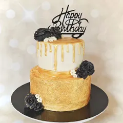 This stunning two-tier cake features a hand-painted gold bottom tier and a top tier with a golden chocolate drip. Adorned with handmade black fondant roses, it's a sophisticated choice for a milestone birthday or anniversary.