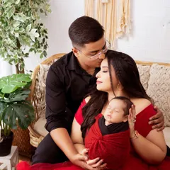 A tender family portrait with a newborn baby. The parents' loving expressions and the baby's peaceful sleep create a timeless and emotional image.