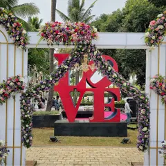 A modern and romantic entrance featuring white arches adorned with flowers, perfectly framing a large red "LOVE" sculpture. It's a perfect photo opportunity for guests.