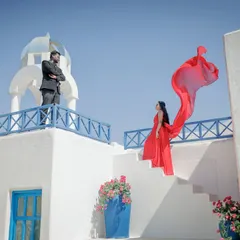 A vibrant, Santorini-themed set provides a stunning backdrop for this dramatic shot. The flowing red dress against the crisp white and blue architecture creates a high-impact, movie-poster look for your pre-wedding album.