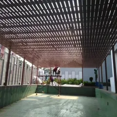 Tipwood being used to create a slatted pergola roof over a swimming pool area. It's a durable and weather-resistant alternative to natural wood.