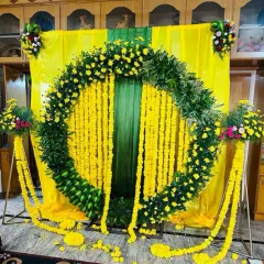 The complete Haldi setup with the marigold arch, yellow fabric backdrop, and floral stands.