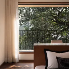 In the son's bedroom of our Multilevel House, the study table flows seamlessly into the platform bed. This integrated design keeps the room uncluttered and maximizes the connection to the two large windows and the nature beyond.