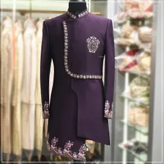 For the modern groom who wants something unique for his Sangeet or engagement. This is an asymmetrical Indo-western suit in a deep purple, featuring intricate embroidery on the cuffs, collar, and hem. It’s a perfect fusion of traditional design and contemporary tailoring.