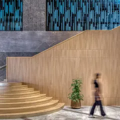A curved wooden staircase and modern jali screen in the Aurobindo Orbit lobby in Hyderabad. This juxtaposition of materials and forms creates a unique design language, turning a functional lobby into a memorable architectural experience.
