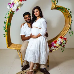 For a more modern and styled maternity shoot, I use props like this heart-shaped frame and a clean background. This shows a different style, focusing on the couple in a beautifully composed studio setting.