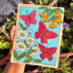 Holding the butterfly and flower painting in my garden. The natural sunlight makes the colors of the acrylic paint look bright and cheerful.