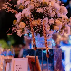 A charming detail from a Sangeet tablescape. A cute, framed quote, "You're the gin to my tonic," sits beside elegant spiral candles and a fresh white floral arrangement, adding a personal and playful touch.