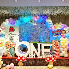 A vibrant and playful Cocomelon themed first birthday party. This full stage setup is packed with character cutouts, a massive rainbow balloon arch over a sparkling backdrop, and large "ONE" marquee letters, ready for a day of fun.