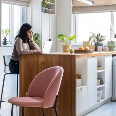 For the 'Footloose' studio apartment, we designed a multifunctional kitchen island that acts as a workspace, dining table, and storage hub, seamlessly blending the kitchen with the living area.