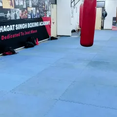 Another angle of our gym floor, showing the heavy bags and the "Shaheed Bhagat Singh Boxing Academy" banner. This is our home.
