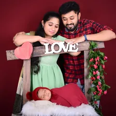 Welcoming a newborn is a moment of pure love. Here, new parents gaze lovingly at their sleeping baby, using a simple 'LOVE' prop to perfectly frame this special time in their lives.