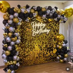 A luxurious black and gold theme featuring a gold shimmer wall. The wall is framed by an L-shaped balloon arch and lit by a "Happy Birthday" neon sign.