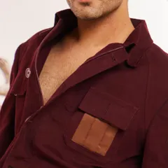 A close-up of the maroon shacket's collar and pocket area. This view shows the texture of the fabric and the precisely stitched leather patch, details that define our quality.