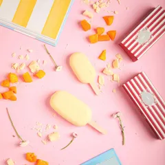 A flat lay of our mango white chocolate ice cream bars, surrounded by pieces of dried mango and white chocolate shavings, showing the real ingredients we use.