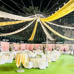This is a dining area setup for an outdoor Sangeet or reception. I used a canopy of yellow and white drapes with strings of fairy lights to create a festive ceiling. The round tables are arranged on the lawn, creating a relaxed and celebratory atmosphere for the meal.