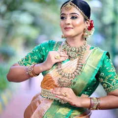 A beautiful bride in a green and orange Kanjeevaram saree. We designed the blouse with detailed Maggam work to match the richness of the silk, creating a perfect bridal ensemble.