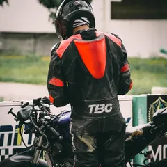 A rider seen from behind, standing with his bike. This moment reflects the mental preparation and focus I instill in my students before every single session on the track.