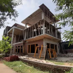A multi-story institutional building taking shape. This image captures the raw structure, with its concrete slabs and brick infill walls, forming the solid bones of the future space.