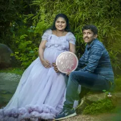 A happy gender reveal moment in a beautiful garden. The couple holds an "It's a girl" sign, sharing their joy in a serene, natural setting.