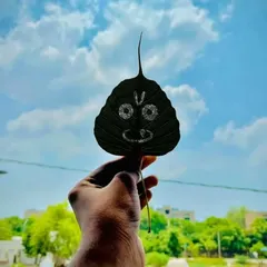 Jai Jagannath. Here is a simple yet devotional carving of Lord Jagannath's face. The dark leaf provides a beautiful contrast, making the features stand out clearly against the bright sky.