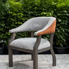 The Versa Armchair, a seamless blend of comfort and modern design. We used a soft, textured bouclé for the seat and a rich burnt orange accent on the outer back, set against a solid ash wood frame with a unique zig-zag leg design.