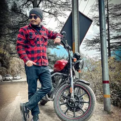 A stylish portrait with a red Royal Enfield on a mountain road. I love finding unique locations for pre-wedding shoots that tell a story about the couple.