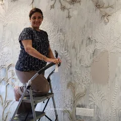 Here I am, working on a large, nature-inspired mural. The piece features a variety of sculpted plants and flowers, creating a rich tapestry of textures that brings the wall to life.