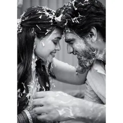 An intimate moment from a Haldi ceremony, captured in soft black and white. The focus is entirely on the couple's tender connection, their foreheads touching amidst the playful mess.