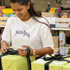 A glimpse of our wrapping process. Here, a member of our team is expertly finishing a gift wrapped in lime green paper with a chic black and white stitched ribbon, ensuring every bow is perfect.
