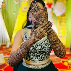 This bride is showing off her full-arm mehndi. The design includes traditional figures and patterns that cover her hands and arms completely for a classic bridal look.