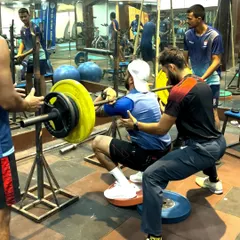 Coaching a heavy back squat with an athlete using heel elevation to improve depth and posture. My hands-on approach ensures that even during maximal effort lifts, technique is never compromised.