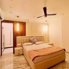 This bedroom design focuses on a soothing, neutral palette of beige, white, and wood. The upholstered headboard and warm pendant lights create a cozy and inviting atmosphere, while the wood paneling adds texture and warmth.