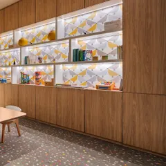 The kids' play area at the Elevate Clubhouse features cheerful wallpaper and custom wood cabinetry with integrated lighting. We added windows to what was initially a closed-off space to bring in natural light and create a bright, engaging environment.