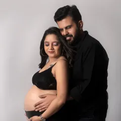 A powerful and intimate portrait. The couple is dressed in black, with the focus on the bare baby bump, symbolizing their shared creation.