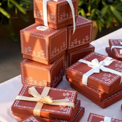 A stack of beautifully packaged gift boxes from Patrika Gift Shop, ready to be shared. The soft, natural light highlights the delicate design and ribbon details, evoking a sense of anticipation and celebration.
