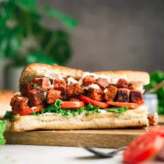 A hearty and delicious vegan sub sandwich, filled with seasoned tempeh, fresh lettuce, and tomatoes.
