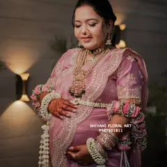 For this beautiful mom-to-be's baby shower, I created a full set of fresh flower jewellery. The look features a delicate floral shela, heavy kalire made from jasmine and rose, and matching armlets, all designed to complement her pink saree and make her feel special.
