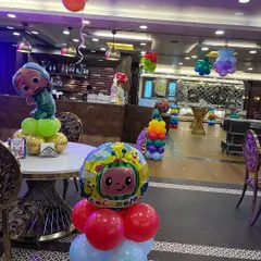 Close-up of a Cocomelon table centerpiece, combining character foil balloons with colorful latex balloons to decorate the guest tables.