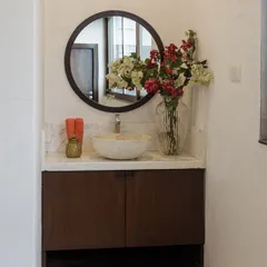 This is a bathroom I designed for a private gym space. The focus was on clean lines and durable materials, featuring a dark wood vanity, a terrazzo-style vessel sink, and a simple round mirror for a functional yet stylish look.