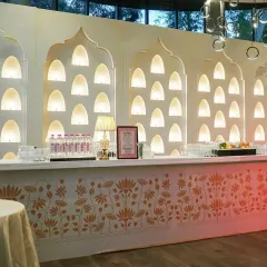 This elegant bar was custom-built for a classic wedding, featuring a backdrop of softly lit Mughal-style arches and a counter decorated with a golden lotus pattern.