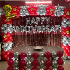 This rectangular backdrop combines a metallic shimmer curtain with a full balloon frame in red, silver, and chrome. The "Happy Anniversary" foil letters make it a complete and festive setup for a lively party at home.