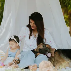 The family's gentle German Shepherd joins the photo, resting its head on the mother's lap. This shows the beautiful bond between a child, her mother, and their loving pet.
