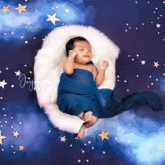 We create dreamy, celestial scenes like this starry sky theme for your newborn. The baby rests on a soft, crescent moon prop against a deep blue backdrop filled with twinkling stars, perfect for a magical first photoshoot.