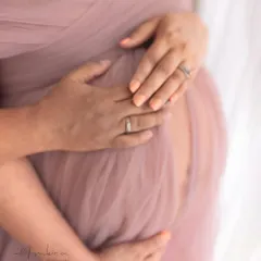 A close-up on the hands cradling the bump, a simple yet powerful gesture of love and protection. This shot captures the details and the deep connection of this special time.