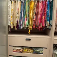 A close-up of a perfectly organized saree collection. We use specialized hangers that prevent creasing and allow each saree's color and design to be visible. Blouses are stored in clear-front drawers below for easy pairing.