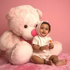 A sweet baby poses with a giant pink teddy bear in our studio. This is the "before" shot for one of our AI transformations.
